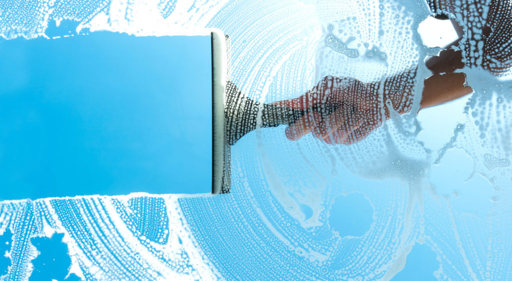 cleaning window with squeegee blue sky